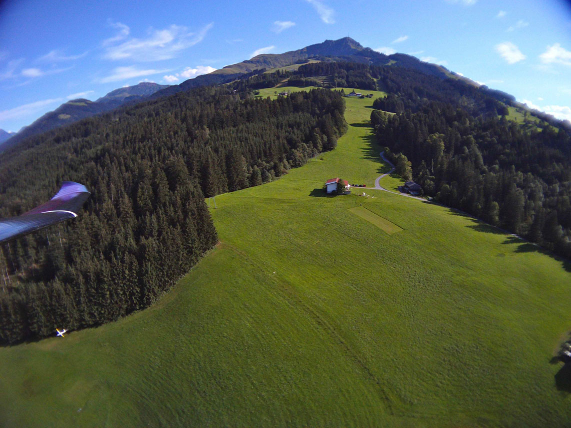 Luftaufnahme des Hangflugplatzes Schneiderberg mit Landebahn. Im Hintergrund das Kitzbüheler Horn